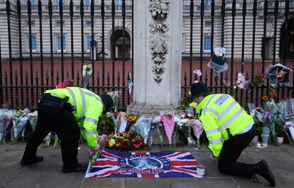 Dos agentes de policía colocan una bandera en un altar improvisado en homenaje a Isabel II ante el palacio de Buckingham, en Londres, este viernes. Con su muerte, la comunidad internacional asiste a la desaparición de una figura que ha atravesado desde un lugar privilegiado las grandes etapas de la segunda mitad del siglo XX y casi del primer cuarto del presente siglo. 