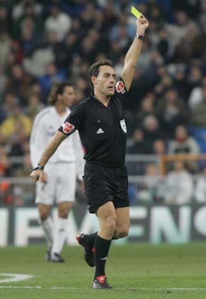 Un árbitro, Pérez Burrull, enseña una tarjeta durante un partido.