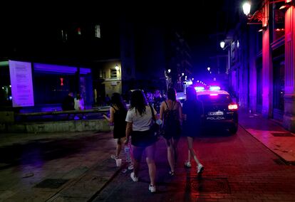 Varios jóvenes turistas pasan ante un coche de policía el 13 de julio en la calle Caballeros del barrio de El Carmen de Valencia.