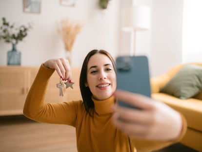 Joven tomándose un selfie con las llaves de su nuevo apartamento.