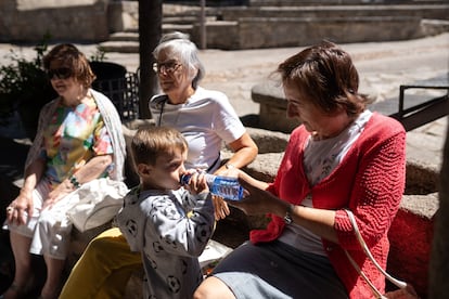 Demetria Delgado le da agua a su nieto en la plaza mayor de Monleras.
