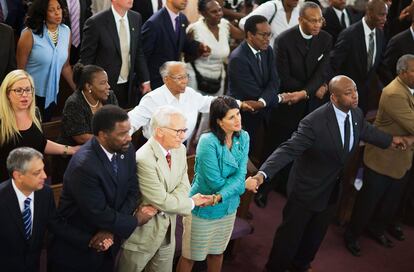 Then-South Carolina Gov. Nikki Haley, center right, joins hands with Sen. Tim Scott, right, at a memorial service at Morris Brown AME Church in Charleston, S.C., on June 18, 2015.