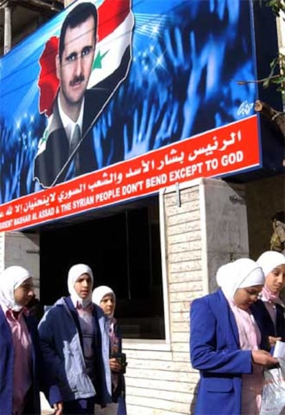 Jóvenes sirias pasan delante de un cartel propagandístico de Bachar el Asad, en Damasco.