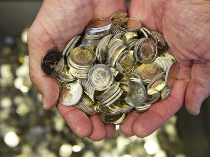 Un hombre sostiene varias monedas de euro.