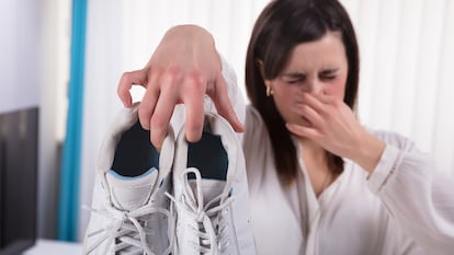 Una mujer tapándose la nariz por el mal olor de unas zapatillas