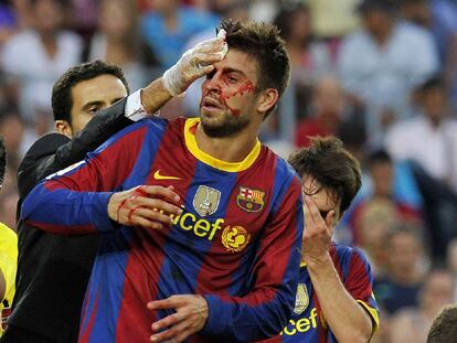 Piqué, con la cara ensangrentada, es atendido por el doctor tras sufrir un golpe en la cabeza.