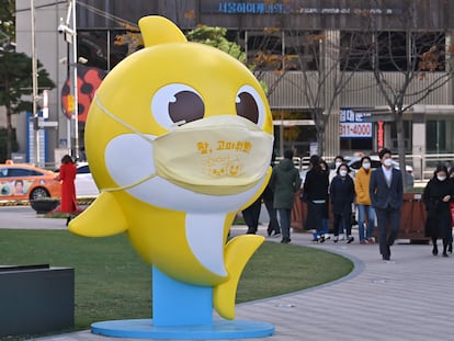 Transeúntes caminan junto a una estatua de uno de los personajes del vídeo de 'Baby Shark' en una plaza de Seúl (Corea del Sur).