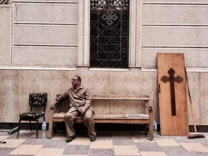 Un hombre espera sentado en un banco fuera de la iglesia de San Jorge de Tanta.