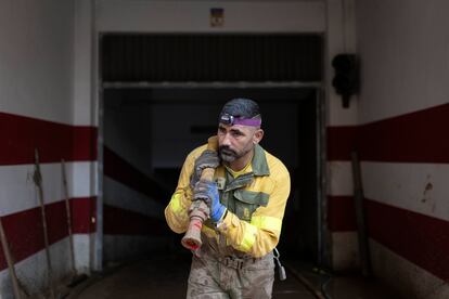 Un bombero de Castilla y Len extrae la manguera de un garaje de Algemes con el que achican agua. 