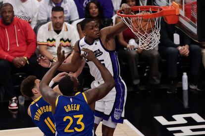 De'Aaron Fox, de los Sacramento Kings, hace un mate frente a Thompson y Green, de Golden State.