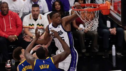 De'Aaron Fox, de los Sacramento Kings, hace un mate frente a Thompson y Green, de Golden State.