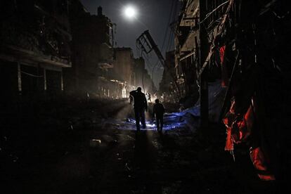 Miembros de la Media Luna Roja de Siria y otros voluntarios buscan víctimas mientras el fuego se extiende tras un ataque aéreo en la ciudad de Douma, a las afueras de Damasco (Siria).