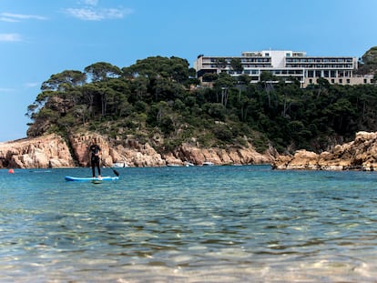 Una mujer practica paddle surf en la playa de Aiguablava, en Begur (Girona), con el parador homónimo al fondo.