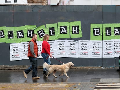 La gente pasa frente a unos carteles colocados por activistas climáticos antes de una protesta por las calles de Glasgow, Escocia, este viernes.