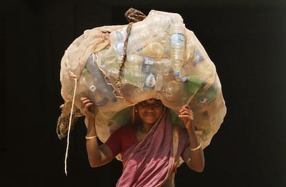 Mulher indiana carrega garaffas pet para vender em um centro de reciclagem, em Bhubaneswar.