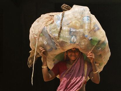 Mulher indiana carrega garaffas pet para vender em um centro de reciclagem, em Bhubaneswar.