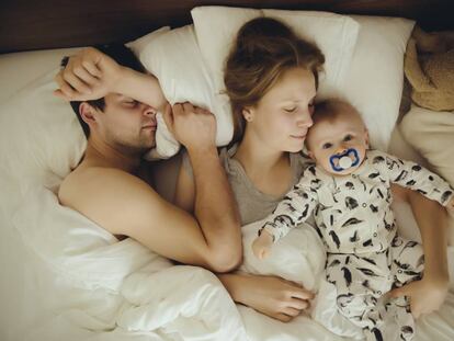 Una pareja duerme con su bebé. 