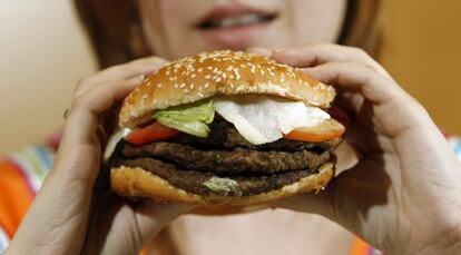 Una mujer se dispone a comerse una hamburguesa triple.