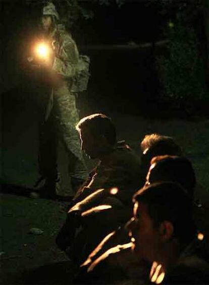 Un soldado de EE UU vigila ayer a algunos de los detenidos durante un operativo contra Al Qaeda en Bagdad.