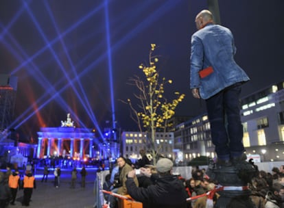 Un seguidor de U2 contempla el escenario subido a una farola tras el muro erigido por los organizadores.