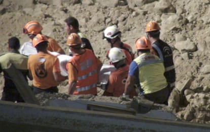 Miembros del cuerpo de bomberos y protección civil trasladan el cuerpo sin vida rescatado de una de las tres personas, que habían quedado atrapadas en su vivienda-cueva.