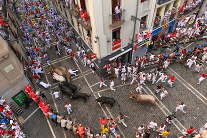 Los toros de la ganadería extremeña de Jandilla a su llegada a la curva de Mercaderes con la calle Estafeta, este viernes durante el sexto encierro de San Fermín.  