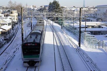 Los trenes de la capital funcionaban con entre 20 y 40 minutos de retraso a primera hora del martes, y muchos servicios rápidos que conectan Tokio con prefecturas limítrofes permanecían suspendidos, aunque los trenes de alta velocidad funcionaban con normalidad. En la foto, un tren circula por las vías después de una fuerte nevada en Tokio (Japón) el 23 de enero de 2018.