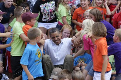 Alumnos de una escuela en Chatfield, Minesota, ayudan a Obama a levantarse después de posar con ellos para una foto.