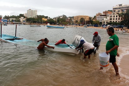 Habitantes de Acapulco (Guerrero) ayudan a llevar una lancha a la orilla del mar entre las intensas lluvias provocadas por la tormenta tropical Carlotta, en junio de 2024.  