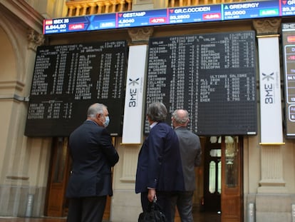 Tres hombres observan los valores económicos de la Bolsa de Madrid.