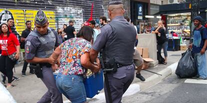 Policiais seguram vendedora ambulante.