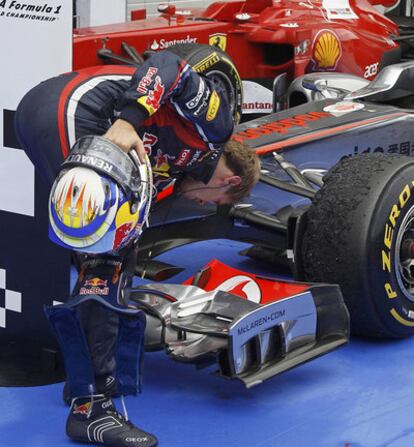 Sebastian Vettel curiosea el McLaren de Jenson Button, el ganador, cuyos neumáticos acabaron muy degradados.