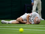 Adrian Mannarino of France lies on the ground in pain during the men's singles first round match against Switzerland's Roger Federer on day two of the Wimbledon Tennis Championships in London, Tuesday June 29, 2021. (AP Photo/Kirsty Wigglesworth)