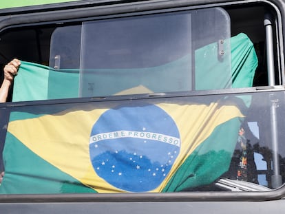 Un partidario de Bolsonaro exhibe una bandera de Brasil en un autobús tras ser desmontado el campamento de bolsonaristas que se había levantado enfrente del cuartel general del Ejército, en Brasilia.
