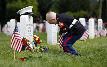 Christian Jacobs, de 5 años de Hertford, Carolina del norte, vestido como un marino, intenta colocar una bandera frente a la lápida de su padre en el cementerio nacional de Arlington en Arlington, Virginia.