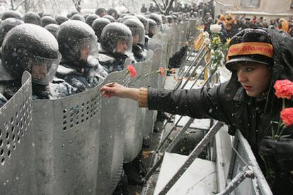 Una manifestante partidaria de Víktor Yúshenko ofrece claveles a los policías <i>antidisturbios</i> concentrados ante la sede presidencial.