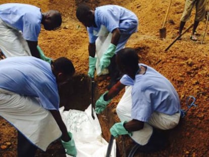 Cuatro voluntarios del personal sanitario entierran a una víctima del ébola en Sierra Leona.