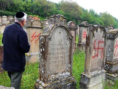 Un hombre observa el estado de algunas lápidas del cementerio de Herrlisheim, pintadas con signos nazis.