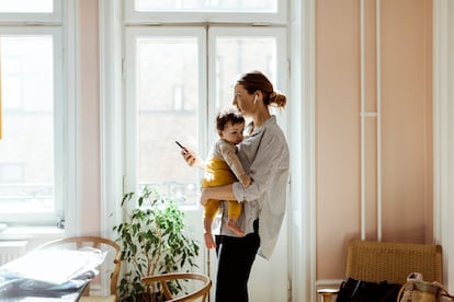 Una directiva atiende al teléfono y a su bebé en brazos, mientras teletrabaja en casa en Estocolmo (Suecia)
