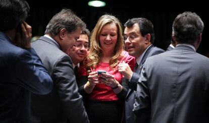 Senadores olham telefone celular no plenário.