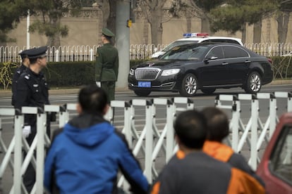 Policía y los agentes de seguridad montan guardia mientras una caravana de automóviles circula a lo largo de una carretera cercana a la residencia de para huéspedes oficiales del Gobierno chino.