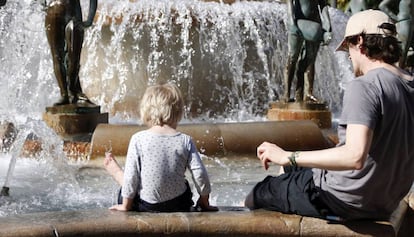 Un hombre y un ni&ntilde;o se refrescan en una fuente de Valencia. 