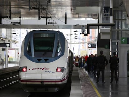 Viajeros en las escaleras mecánicas con sus maletas y un AVE en la estación de Atocha de Madrid.
 
 