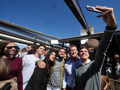 El presidente del PP, Alberto Núñez Feijóo, posa para una foto con jóvenes en un acto de vivienda en Madrid.