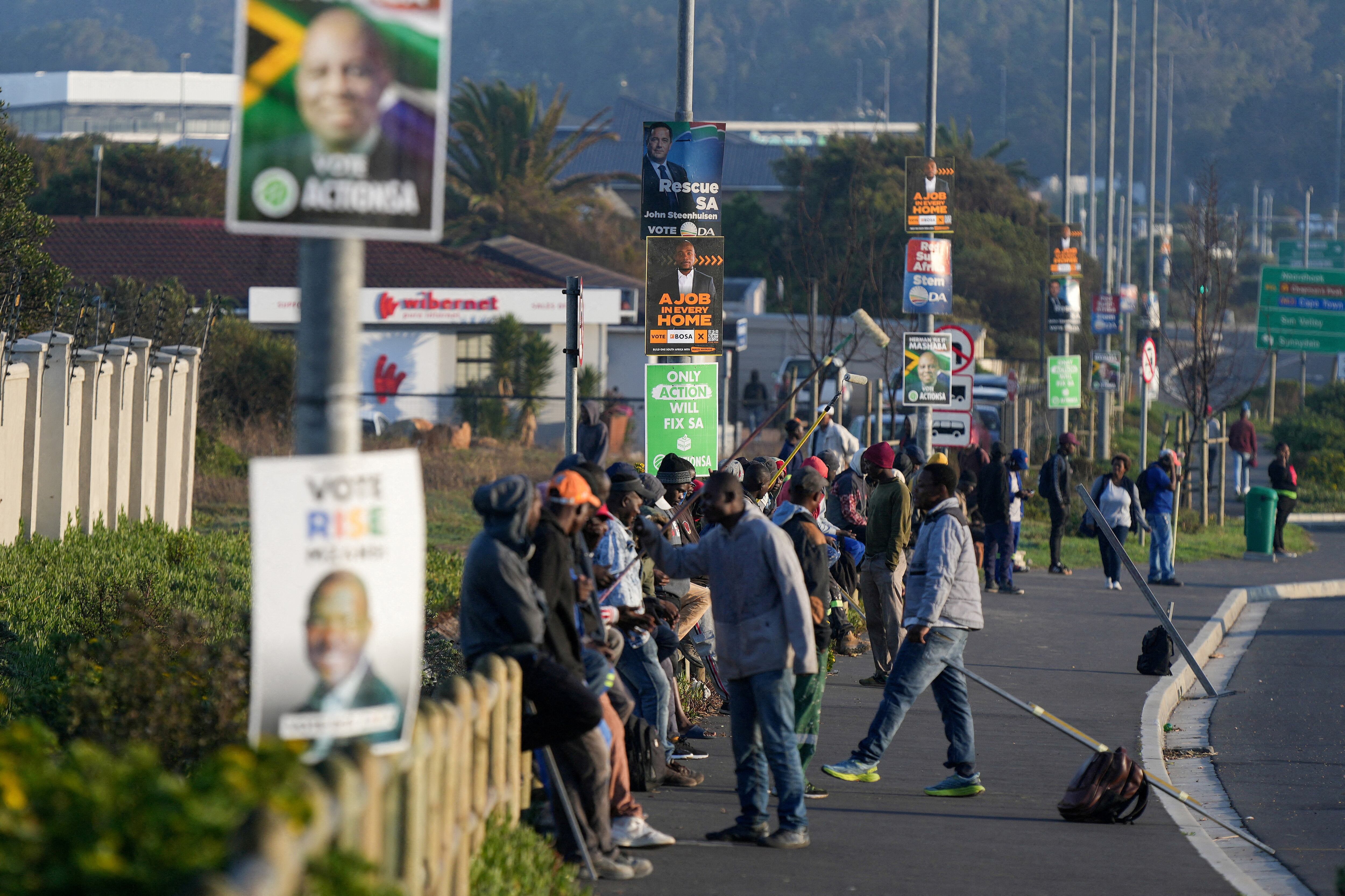 Varios parados hacían fila el 19 de abril para conseguir un trabajo informal en una calle de Ciudad del Cabo llena de carteles electorales.