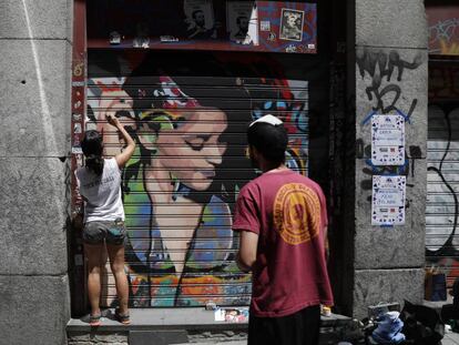 Dos artistas pintan un grafiti en Malasaña.