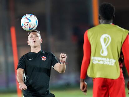 El seleccionador canadiense, John Herdman, controla un balón ante la mirada de Alphonso Davies.