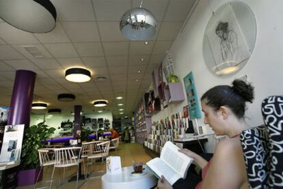 Una mujer lee un libro en la librería Bibliocafé de Valencia.