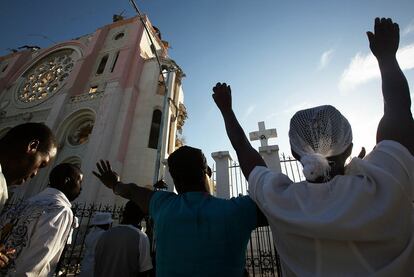 Varias personas rezan durante los oficios celebrados junto a la catedral de la capital de Haití, Puerto Príncipe.