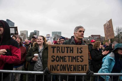 Un hombre de mediana edad sujeta un cartel en la ciudad de Boston con la frase: 'A veces, la verdad es un inconveniente'.